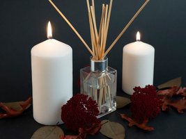 Raumduft und zwei Kerzen mit winterlicher Blumendeko