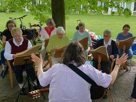 Das Ensemble mit sieben Musikerinnen auf einer grünen Wiese