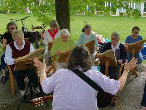 Das Ensemble mit sieben Musikerinnen auf einer grünen Wiese