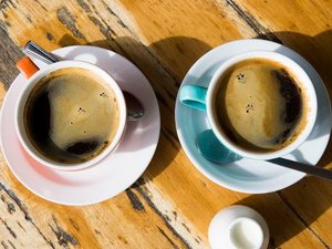 Zwei Tassen schwarzer Kaffee von Oben auf einem Holztisch.