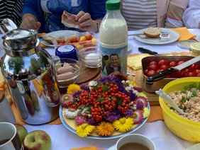 Ein gedeckter Frühstücktisch mit Blumenarrangement in der Mitte.